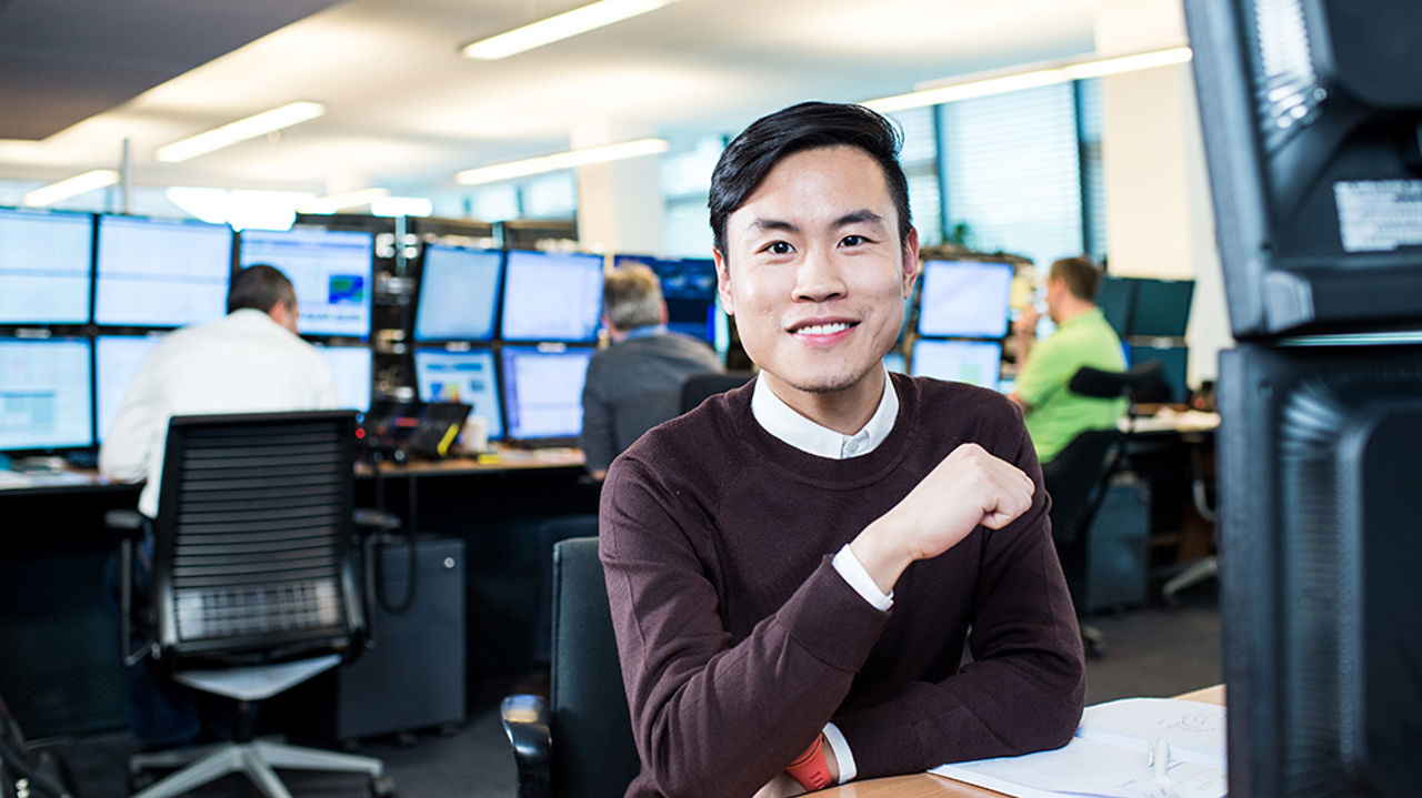 Smiling man sitting in front of trading floor