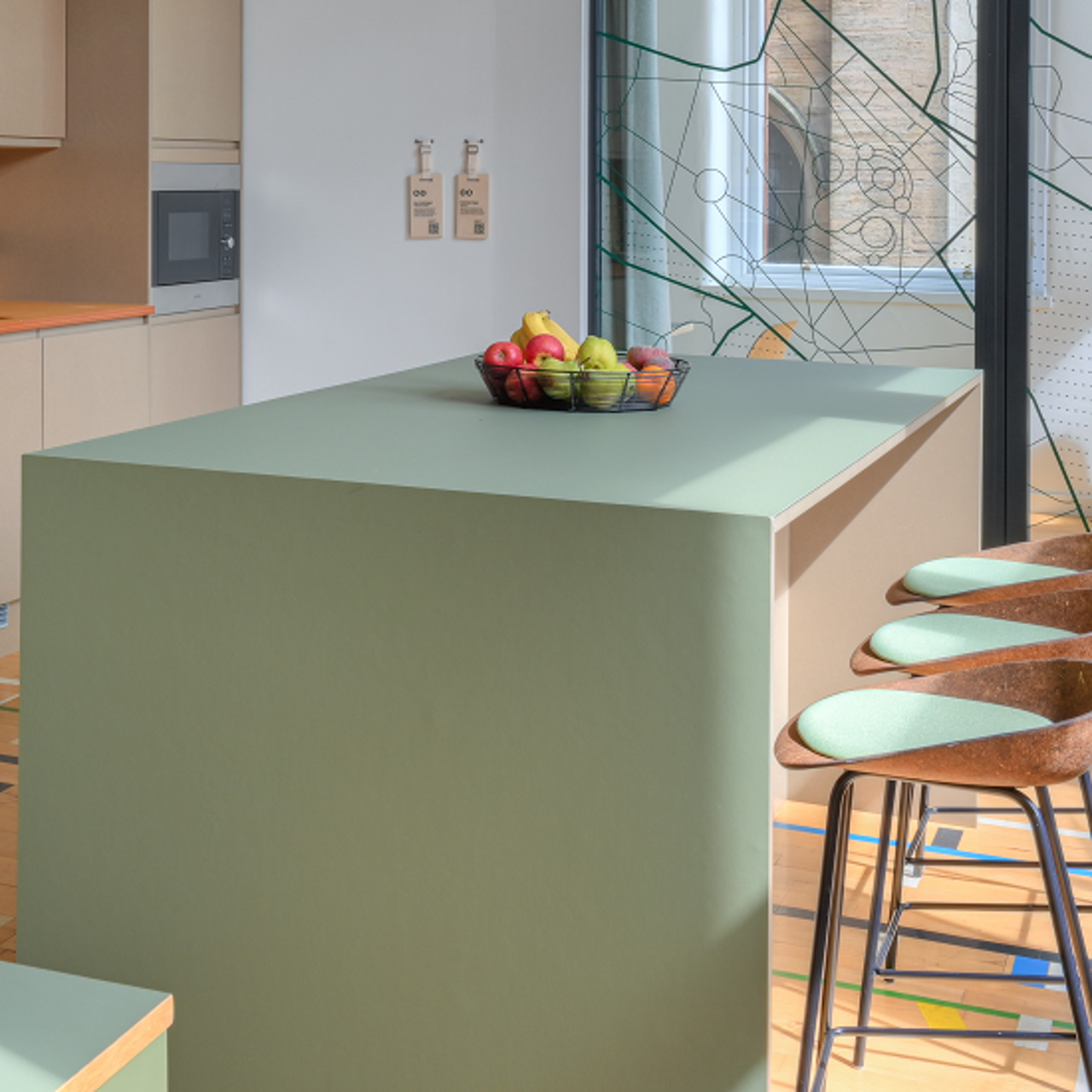 Green kitchen counter with green stools and fruit bowl