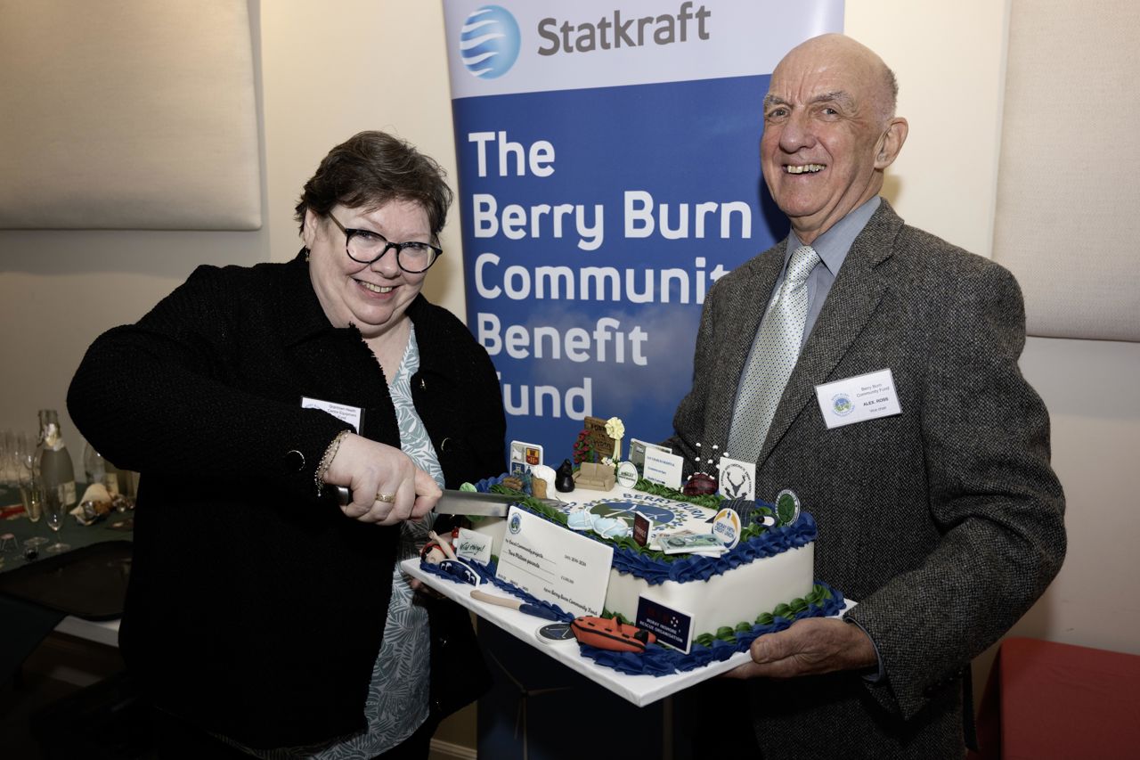 Man and woman smiling and holding a cakr