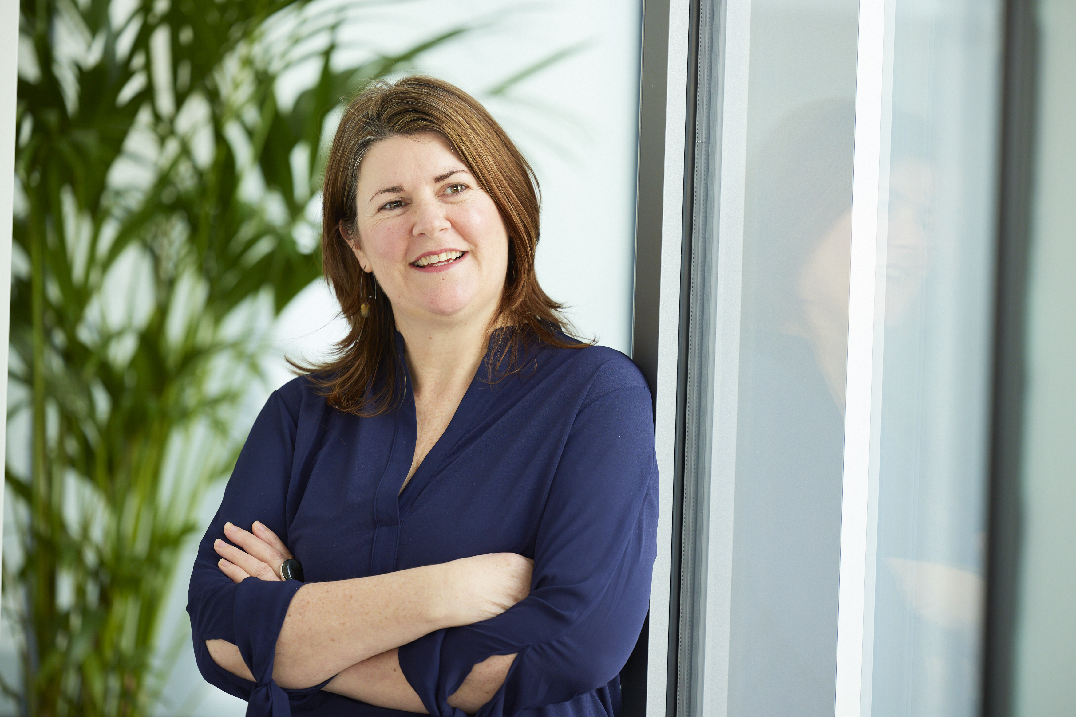 woman with brown hair crossing her arms and smiling
