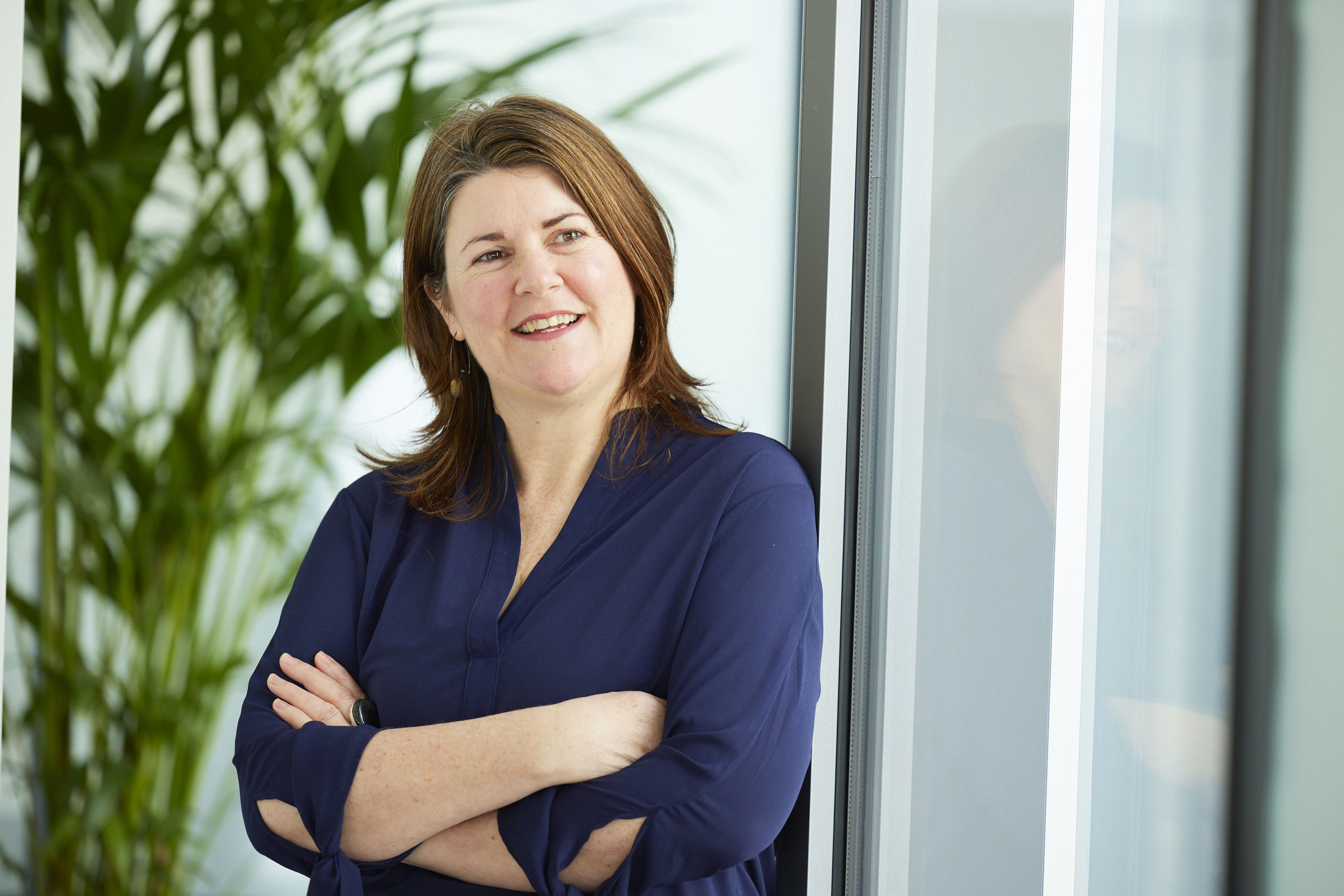 woman with brown hair crossing her arms and smiling